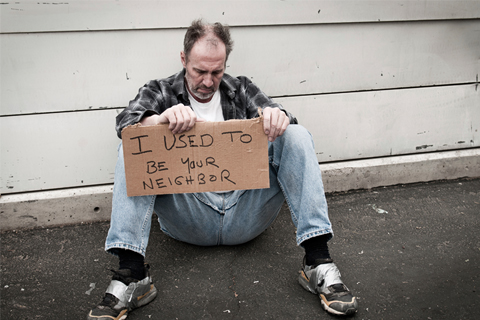 A man sitting on the ground holding a sign.