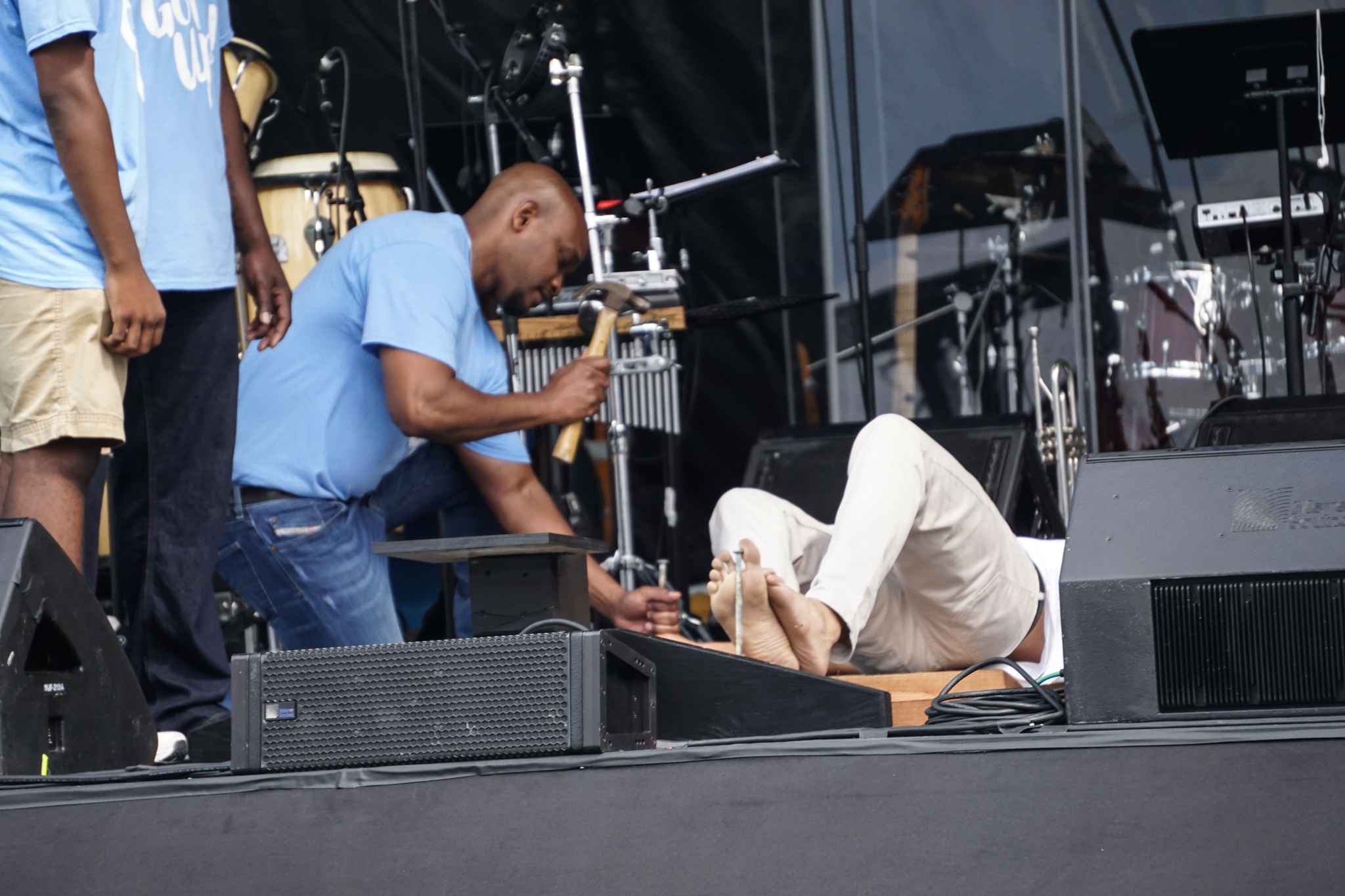 A man is sitting on the ground while another person adjusts his microphone.