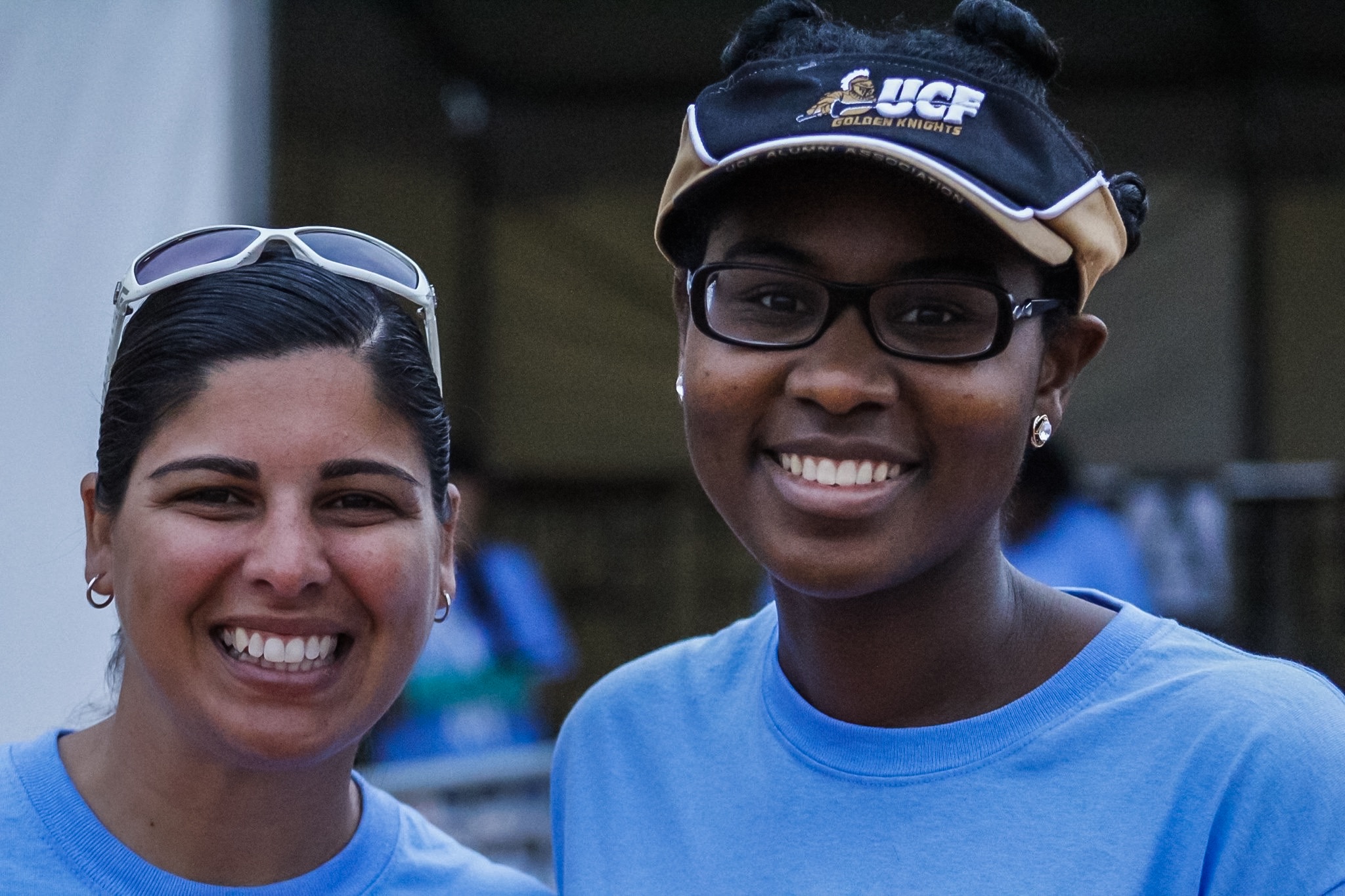 Two women smile for a picture while wearing blue shirts.