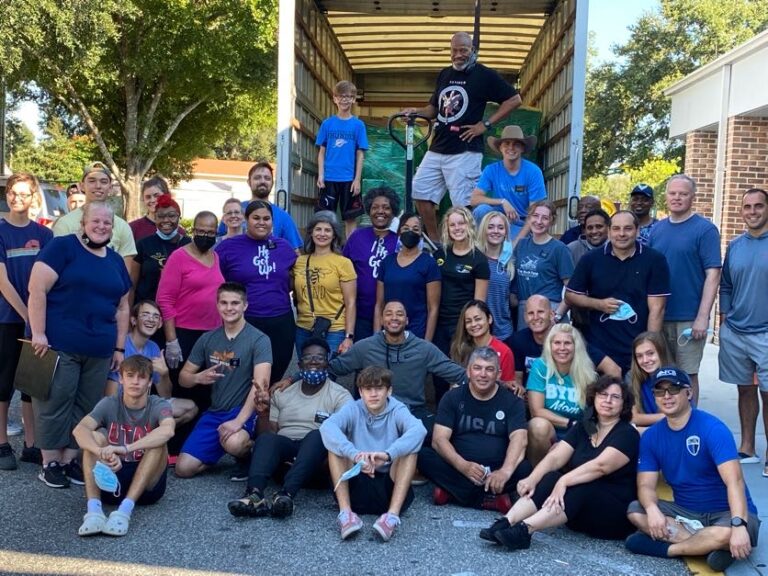 A group of people standing around in front of a truck.