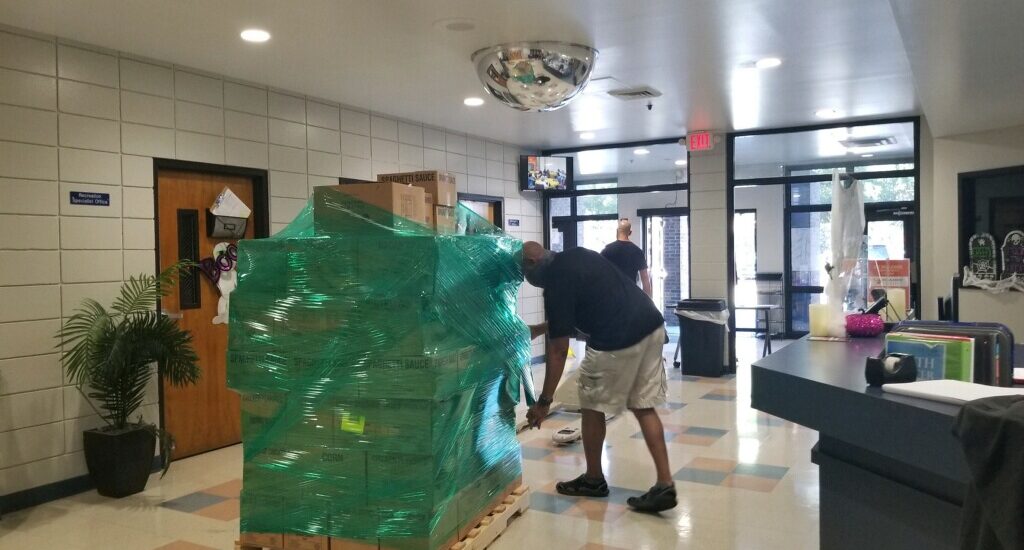 A man moving boxes on top of a wooden pallet.