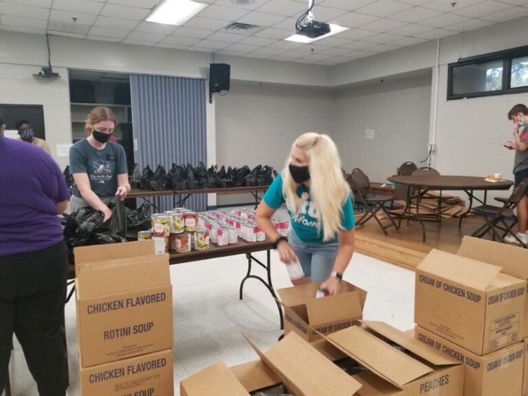 A woman and man in blue shirts packing boxes.